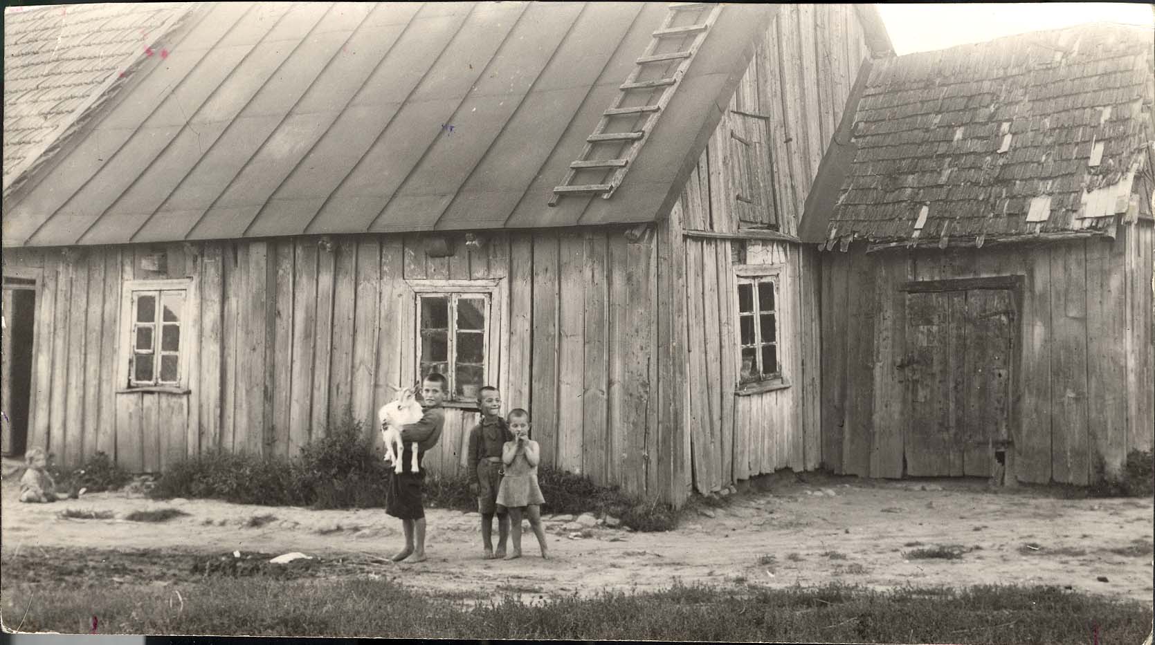 Skaudvilė, Lithuania; children with a goat outside a wooden house